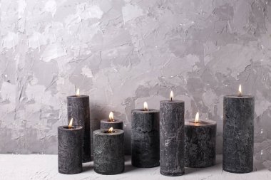 Gri dokulu arka planda siyah yanan mumlar. 