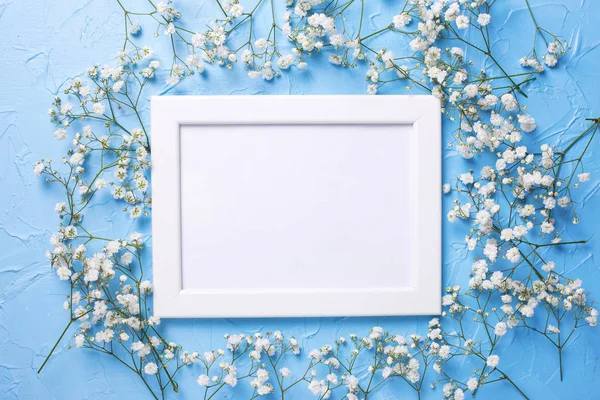 Lege witte frame en verse witte gypsofila bloemen op blauw t — Stockfoto