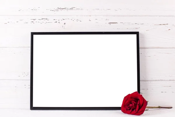 Leere schwarze Rahmenattrappe und rote Rosenblume — Stockfoto