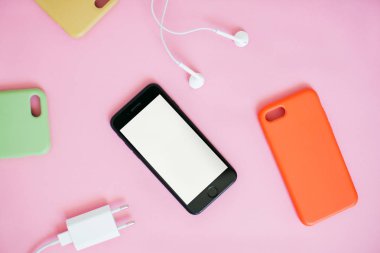 Kulaklıklı ve şarjlı ve silikon kılıflı akıllı telefonun üst görünümü.