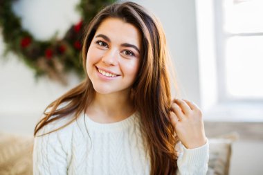 Yeni Yıl ağacıyakınında beyaz rahat kazak genç çekici kadın.