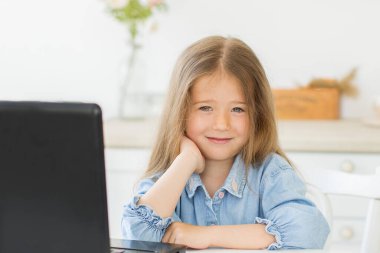 Mesafe öğrenme. Okul konseptine geri dönelim. Güzel anaokulu kızı dijital masaüstü bilgisayarıyla evde geziyor..