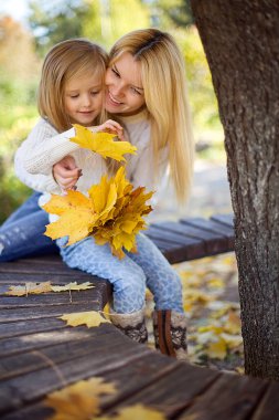 Güzel, mutlu bir anne ve küçük kızı Autumn Park 'ta oynuyorlar..