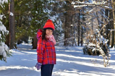 Bir karlı kış gününde ormanda bir yürüyüşe kırmızı şapkalı kız. 