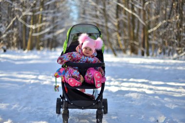 Küçük bir kız pembe şapka ve bir karlı kış gününde ormanda bir yürüyüş için özel iş elbisesi.