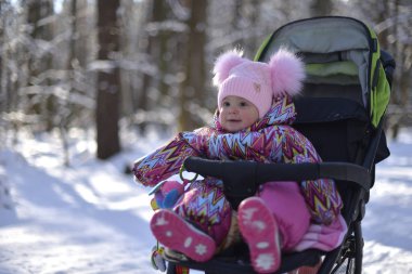 Küçük bir kız pembe şapka ve bir karlı kış gününde ormanda bir yürüyüş için özel iş elbisesi.