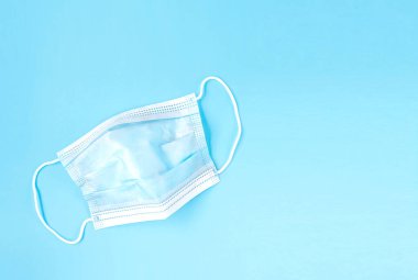 Açık mavi arka planda tek tıbbi maske. Koronavirüs koruma ve kişisel bakım kavramı