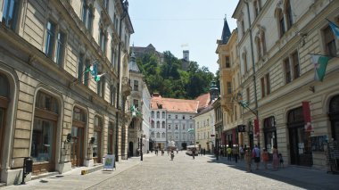 Ljubljana, Slovenya - 07 19 2015 - eski şehir sokak görünümünü ve Ljubljana Kalesi dağda, güneşli bir gün
