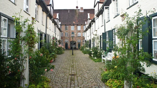 Bellissimo cortile accogliente con vecchie case e fiori nella strada del centro storico, Lubecca, Germania — Foto Stock