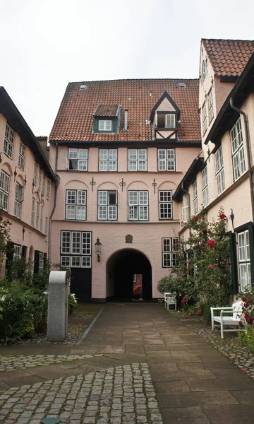 Schöner Innenhof mit Bank, Pflanzen und Blumen in der Altstadt, Lübeck, Deutschland — Stockfoto