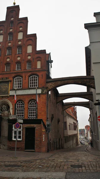 Blick auf Straße mit Backsteinbögen und altem roten Haus, schöne Architektur, Lübeck, Deutschland — Stockfoto