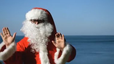 Bir adam Noel Baba kostümlü sahil üzerinde dans ediyor. Seyahat ve tatil