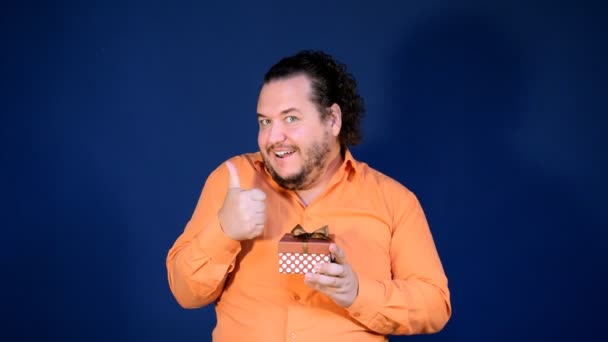 滑稽的胖男人在橙色衬衫打开一个盒子的礼物 生日快乐大惊喜 — 图库视频影像