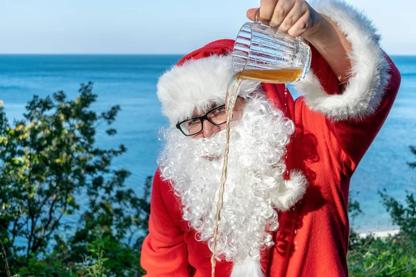 Gruby Mężczyzna Okularach Ubrany Jak Santa Nalewa Piwo Kubka Ziemi — Zdjęcie stockowe