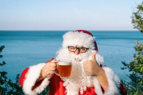 Fat man dressed as Santa drinking beer on the ocean