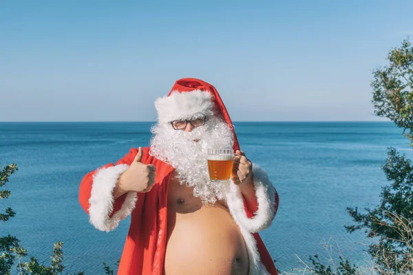 Fat man dressed as Santa drinking beer on the ocean