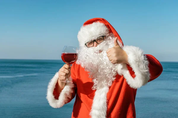 Fet Man Glas Klädd Som Santa Dricker Vin Havet — Stockfoto