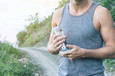 Bir şişe su, okyanusta ayakta tutan atletik bir adam. Spor ve sağlıklı bir yaşam tarzı
