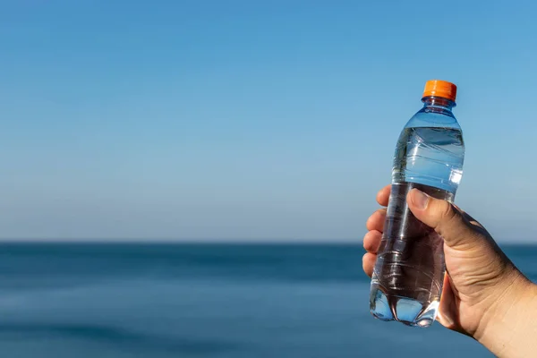 A man holds a plastic bottle of drinking water in his hand