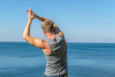 Okyanusun bir ısınma egzersiz yapan erkek.