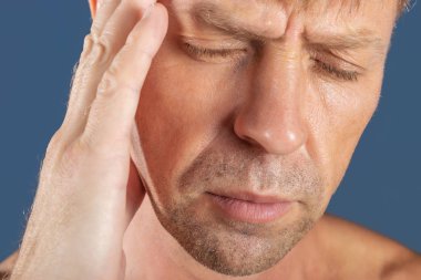 Bir adam mavi zemin üzerine kafasında onun ellerini tutar