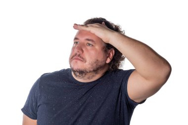 Kendini güneş ışınlarından korumak için şişman adam uzakta gözlerini elini tutarken arıyorsunuz