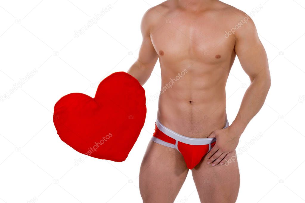Torso of young handsome guy with heart pillow. Sexy portrait of romantic man with valentine on white isolated background