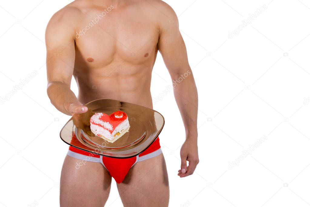 Torso of young handsome guy with heart-shaped cake on a plate. Sexy portrait of romantic man with valentine