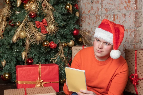 Przystojny Facet Pisze List Santa Siedzący Pod Drzewem Otoczeniu Pól — Zdjęcie stockowe
