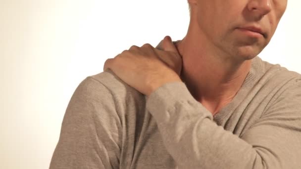 Man massages zijn pijnlijke schouder proberen te verlichten pijn op witte achtergrond. Gezondheidsproblemen — Stockvideo