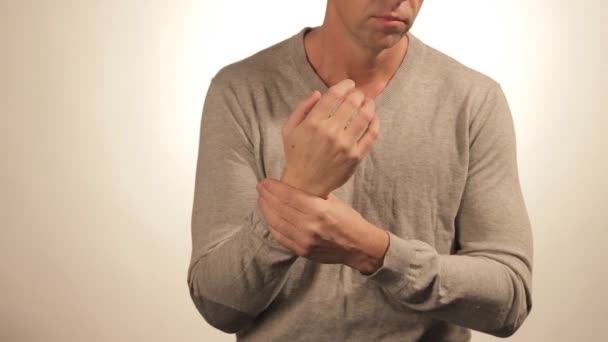 Close-up van man masseren zijn pols op witte achtergrond. Gezondheidszorg en probleem concept — Stockvideo