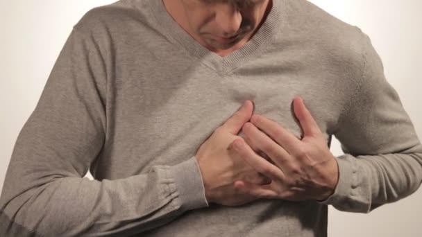 Hombre sosteniendo su pecho con ambas manos, teniendo un ataque al corazón o calambres dolorosos, presionando el pecho con expresión dolorosa sobre fondo blanco. Dolor de corazón severo — Vídeos de Stock