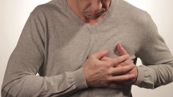 Homme tenant sa poitrine avec les deux mains, ayant une crise cardiaque ou des crampes douloureuses, appuyant sur la poitrine avec une expression douloureuse sur fond blanc. Douleurs cardiaques sévères — Video