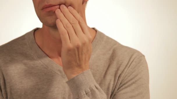 Triste hombre con dolor masajeando su mejilla. Retrato de un hombre sobre fondo blanco. Dolor de muelas — Vídeo de stock