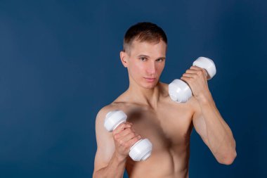 Closeup kaslı bir genç adam mavi arka plan üzerinde halter kaldırma