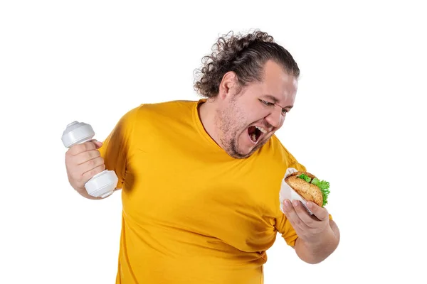 Engraçado homem gordo comendo comida não saudável e tentando fazer exercício isolado no fundo branco — Fotografia de Stock