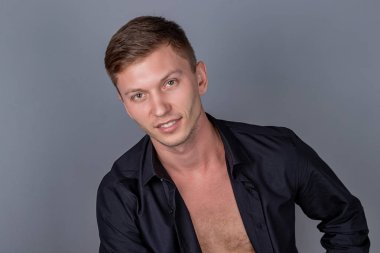 Deri kanepede oturan siyah gömlek giyen seksi yakışıklı adam. Konfor ve rahatlama