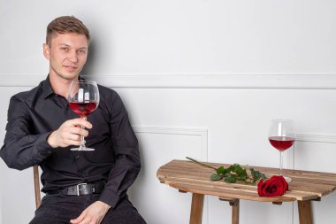 Genç ve yakışıklı bir adam kafeteryada oturmuş kız arkadaşını bekliyor.