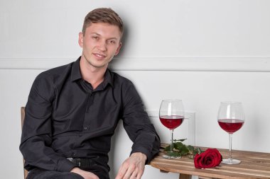 Genç ve yakışıklı bir adam kafeteryada oturmuş kız arkadaşını bekliyor.