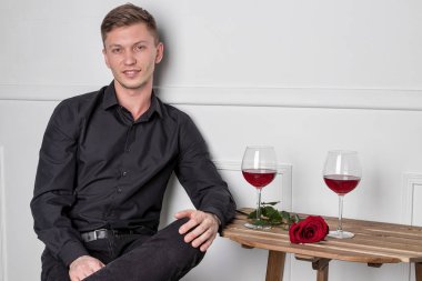 Genç ve yakışıklı bir adam kafeteryada oturmuş kız arkadaşını bekliyor.