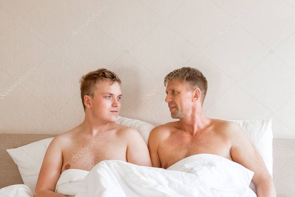 Handsome gay men couple on bed together. Love and relationships