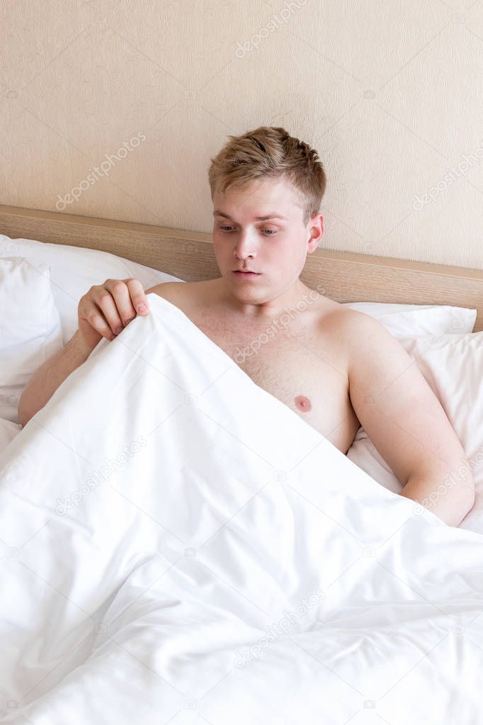Funny guy in bed under the blanket after sleeping. Sexual problems