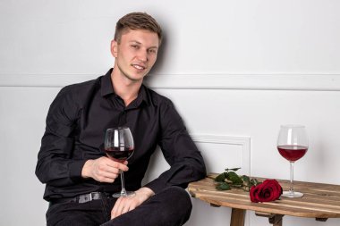 Genç ve yakışıklı bir adam kafeteryada oturmuş kız arkadaşını bekliyor.