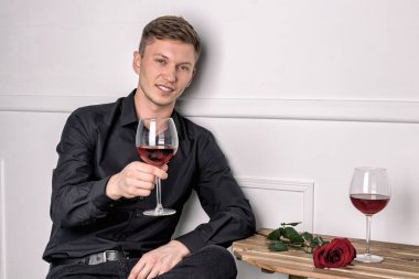 Genç ve yakışıklı bir adam kafeteryada oturmuş kız arkadaşını bekliyor.