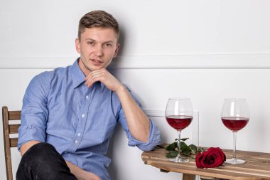 Genç ve yakışıklı bir adam kafeteryada oturmuş kız arkadaşını bekliyor.