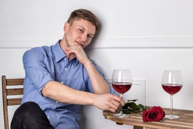 Genç ve yakışıklı bir adam kafeteryada oturmuş kız arkadaşını bekliyor.