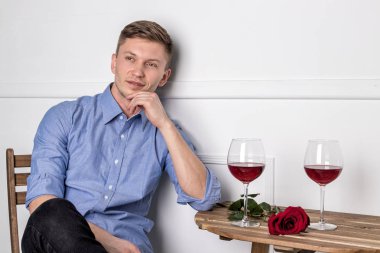 Genç ve yakışıklı bir adam kafeteryada oturmuş kız arkadaşını bekliyor.