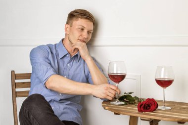 Genç ve yakışıklı bir adam kafeteryada oturmuş kız arkadaşını bekliyor.