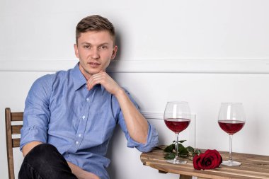 Genç ve yakışıklı bir adam kafeteryada oturmuş kız arkadaşını bekliyor.