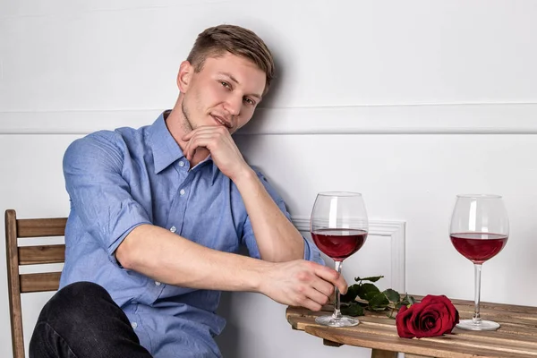 Genç ve yakışıklı bir adam kafeteryada oturmuş kız arkadaşını bekliyor.